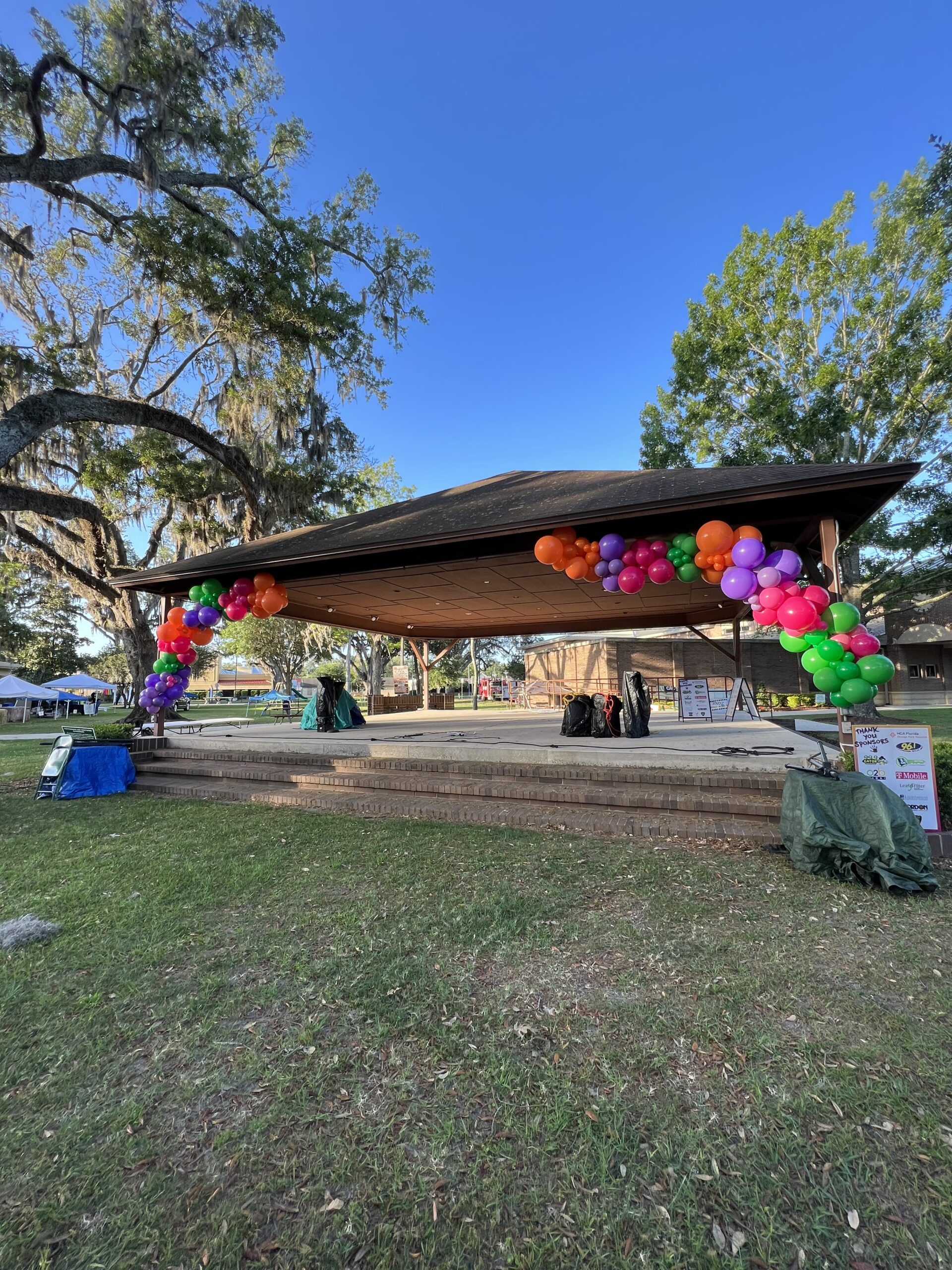 Large colorful balloon garland attached to a public park stage in orange park